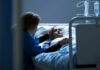 Jailhouse Hustle Targets Dying Veterans Patient in hospital bed comforted by visitor