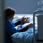 Jailhouse Hustle Targets Dying Veterans Patient in hospital bed comforted by visitor