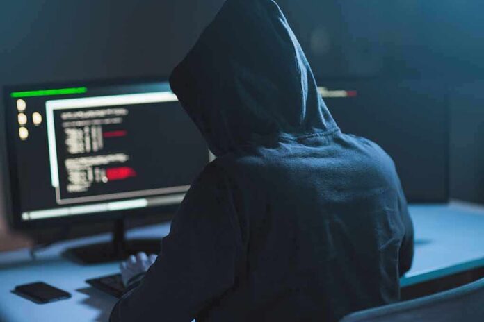 Person in hoodie at dual monitors with code