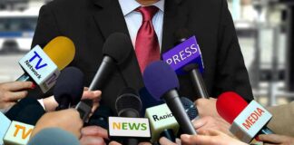 Press microphones surround a suited spokesperson