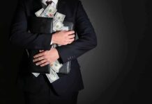 Businessman hugging briefcase stuffed with cash