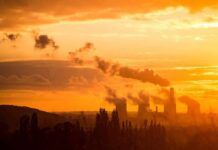 Climate Promises Crumble—Fossils Still Dominate Power plant cooling towers emit smoke at sunset