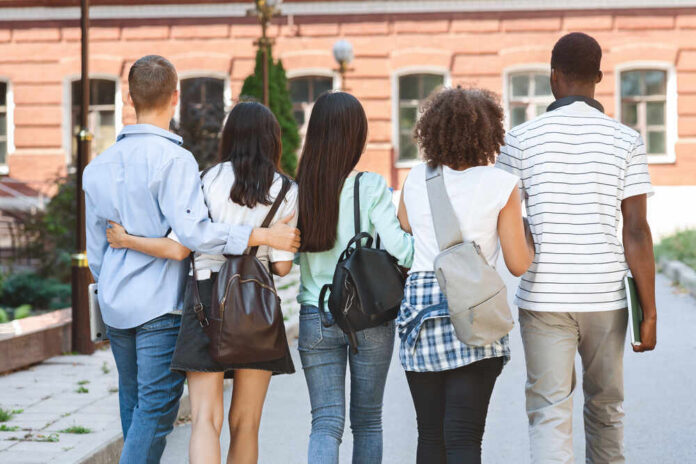 College,Friendship.,Group,Of,Five,Students,With,Backpacks,Walking,At Group of students walking together on campus
