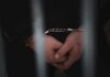 Pardon Outrage: Deportation Vanishes Overnight Close-up of handcuffed hands behind bars