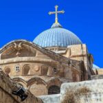 Dome of a historic church with a cross against a clear blue sky