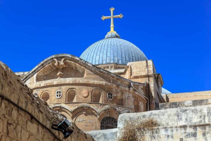 Dome of a historic church with a cross against a clear blue sky