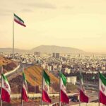 Iranian flags overlooking a sprawling city and distant mountains