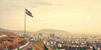 Iranian flags overlooking a sprawling city and distant mountains
