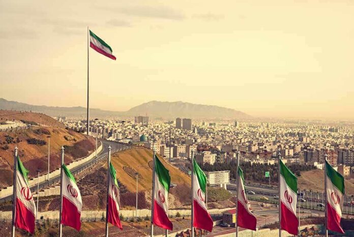 Iranian flags overlooking a sprawling city and distant mountains