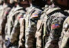 Doctors, Coders Targeted—Draft Reboot? Soldiers in camouflage with American flag patches standing