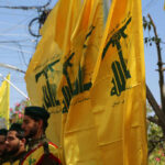 Men standing with yellow flags wearing green berets