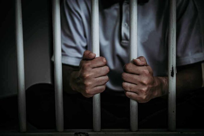 shutterstock_1012787206-1 person gripping prison bars