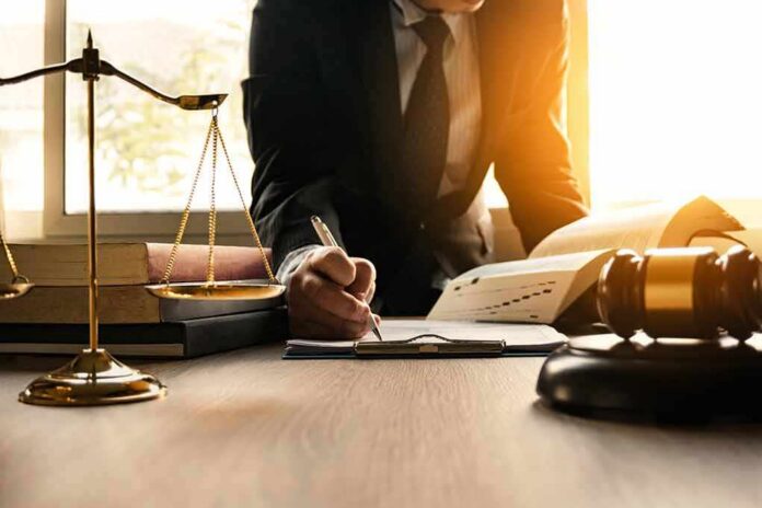 shutterstock_1029430792 Lawyer writing at desk with scales and gavel
