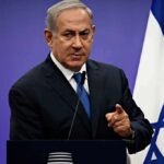 Netanyahu Shocker: Tehran Came For Family man in suit speaking at podium with Israeli flag