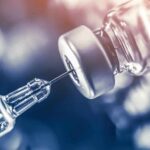 Shock Ultimatum: Accept Exemptions Or Lose Millions syringe needle drawing liquid from a vaccine vial