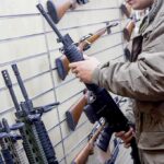 Person examining a black rifle in a gun store