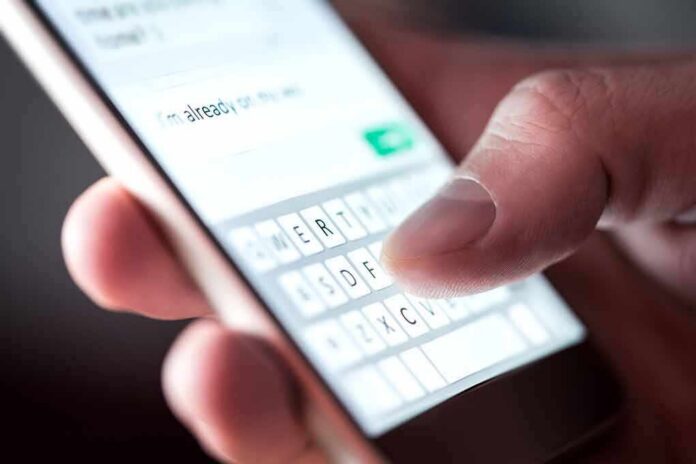 Hand typing on smartphone touchscreen keyboard