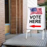 Undercover Sting Triggers State Threats Sidewalk sign with American flag directing to a polling place