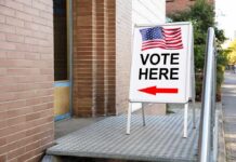 Undercover Sting Triggers State Threats Sidewalk sign with American flag directing to a polling place