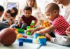 toddlers playing with colorful building blocks on a mat