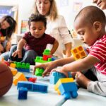 Audit Flags Chaos In Child-Care Payouts toddlers playing with colorful building blocks on a mat