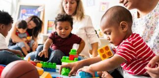 toddlers playing with colorful building blocks on a mat