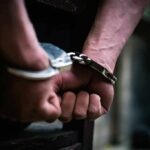 Masked Menace Hunted Coast-To-Coast hands in handcuffs behind back