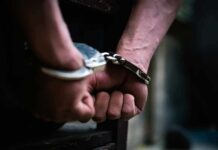 Masked Menace Hunted Coast-To-Coast hands in handcuffs behind back