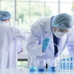 Insiders Circle Cancer Trial Payouts Scientist pipetting blue liquid into test tubes in a laboratory