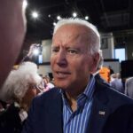 Brand Turns Toxic—Dem Insiders Ditch Biden man in suit interacting with people at an indoor event