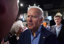 Brand Turns Toxic—Dem Insiders Ditch Biden man in suit interacting with people at an indoor event