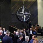 Germany’s Mega Spend – NATO Balance Upended conference attendees under large star emblem in modern chamber