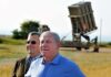 two men standing near a missile defense launcher outdoors