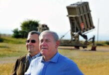 two men standing near a missile defense launcher outdoors