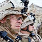 Heatwaves Cripple Drills — Readiness Suffers Two soldiers in military gear looking serious in an outdoor setting