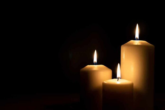 shutterstock_1511835401 Three lit candles against a dark background