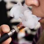 Doctors Warn: Vaping Supercharges Ozempic Misery Close-up of a person vaping, exhaling smoke clouds