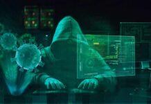 Hooded hacker at computer with digital virus graphics