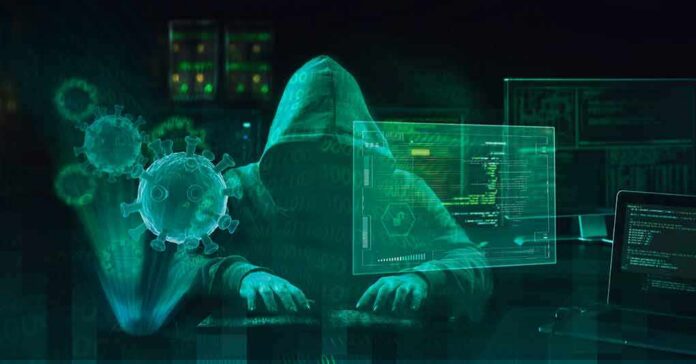 shutterstock_1700246950 Hooded hacker at computer with digital virus graphics