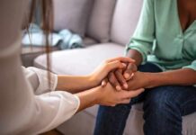 Two people holding hands on a couch