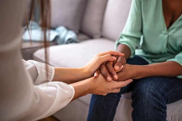 shutterstock_1918956056 Two people holding hands on a couch