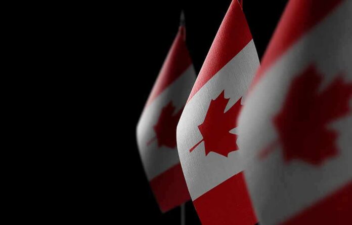 shutterstock_1950525973 Canadian flags with maple leaf on dark background