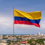 Colombian flag waving over a coastal city skyline