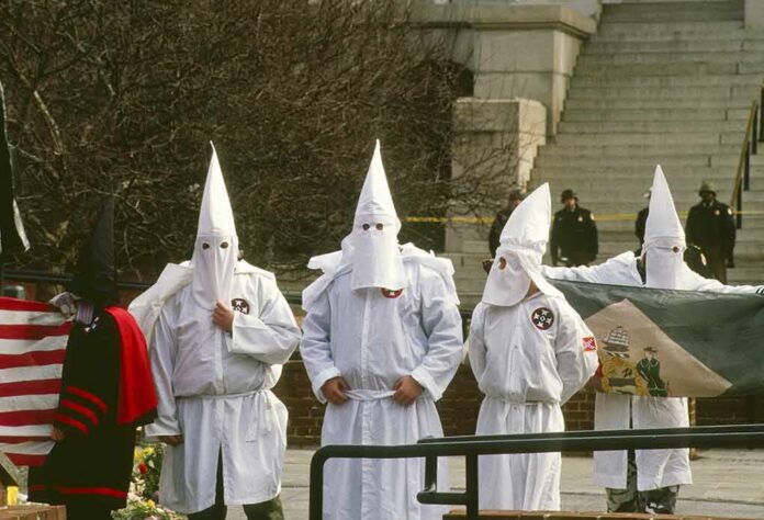 shutterstock_711541543 ku klux klan members in white robes and hoods at a public gathering