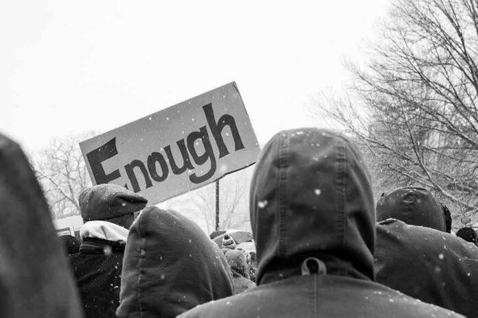 shutterstock_1055553401 crowd in winter coats at a protest holding a sign
