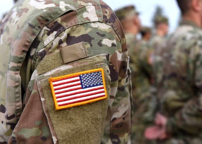 shutterstock_1224308800 U.S. flag patch on a camouflage military uniform