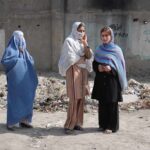 40% Error Rate – Afghan Vetting Gaps Exposed Three women in traditional attire standing in an urban setting with debris in the background