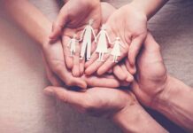 Hands holding a paper cutout family