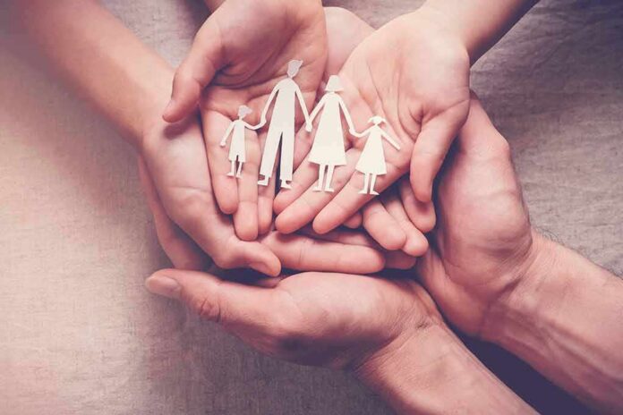 shutterstock_1476188642 Hands holding a paper cutout family