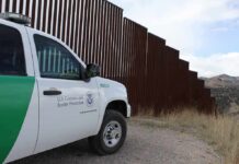 Skies Turn Hostile – Laser Smackdown At The Border Border patrol SUV parked beside tall steel border fence